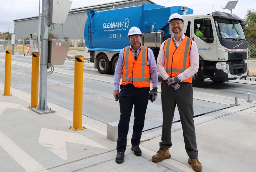 Two people wearing high visibility clothing and protective helmets standing in front of blue waste truck with Cleanaway logo.