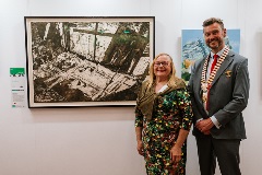 Two people standing proudly in front of an artwork.