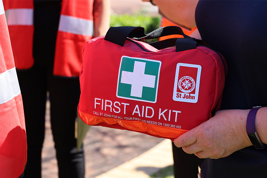 red first aid kit in hands of person