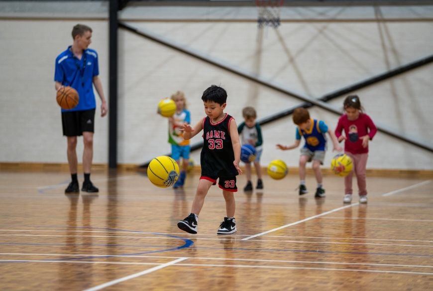 A class of kids learning basketball at George Burnett Leisure Centre
