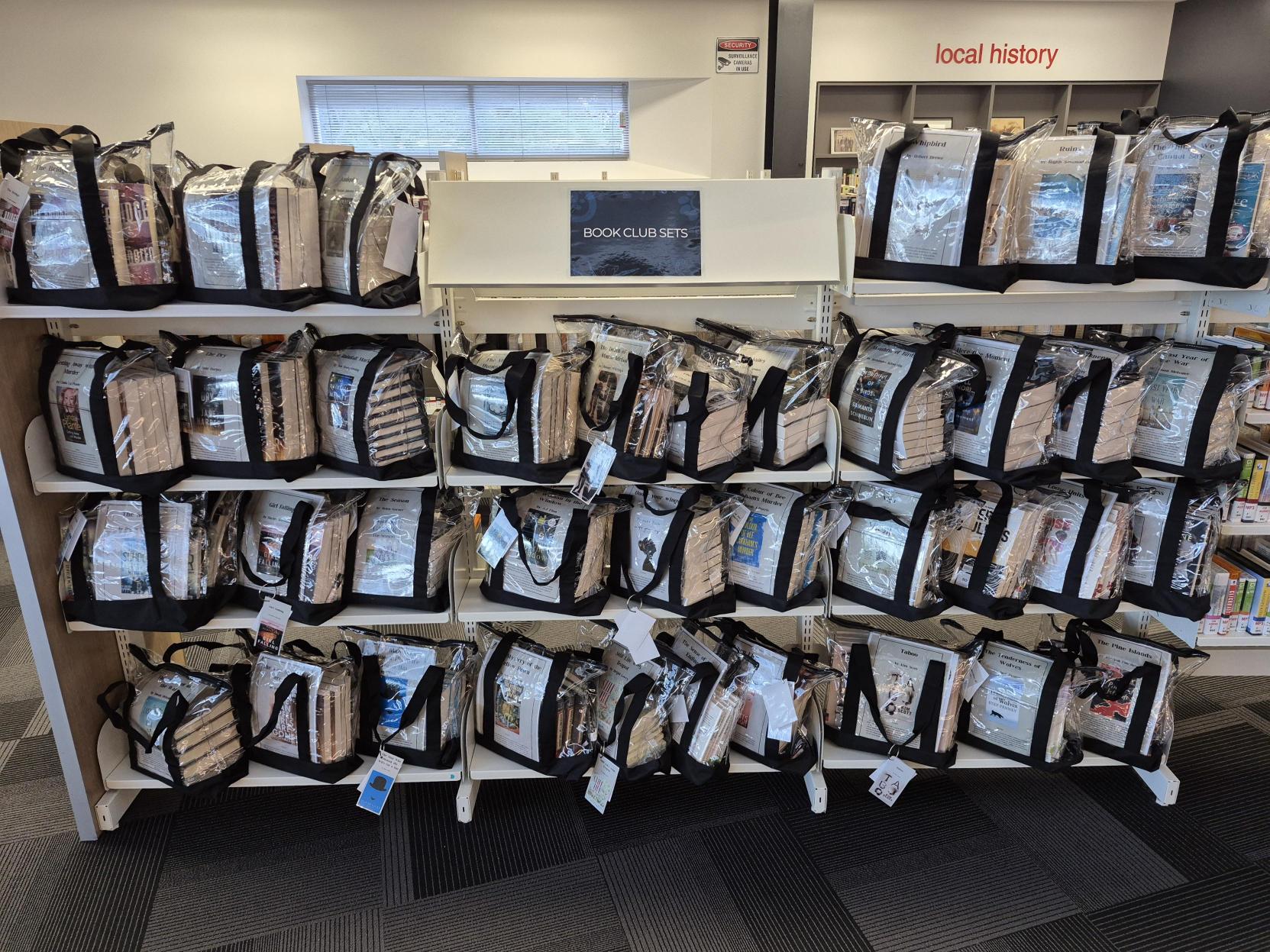 Various books in clear plastic bags stacked on a shelf