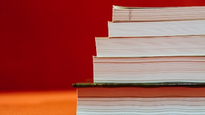 A pile of books set against a red backdrop