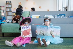 Twolittlegirlsindressupsittingonthefloorreadingpicturebooks