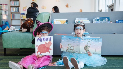 Twolittlegirlsindressupsittingonthefloorreadingpicturebooks