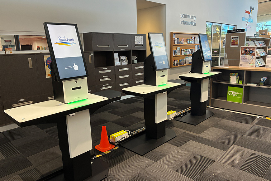 Three self-service library kiosks in a row.