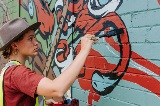 ArtistMikaelaMillerpaintswallwithblackpaintbrush