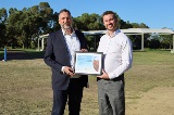Twosmilingpeopleholdingaframedcertificate