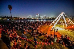 An outdoor crowd watching aerial performer