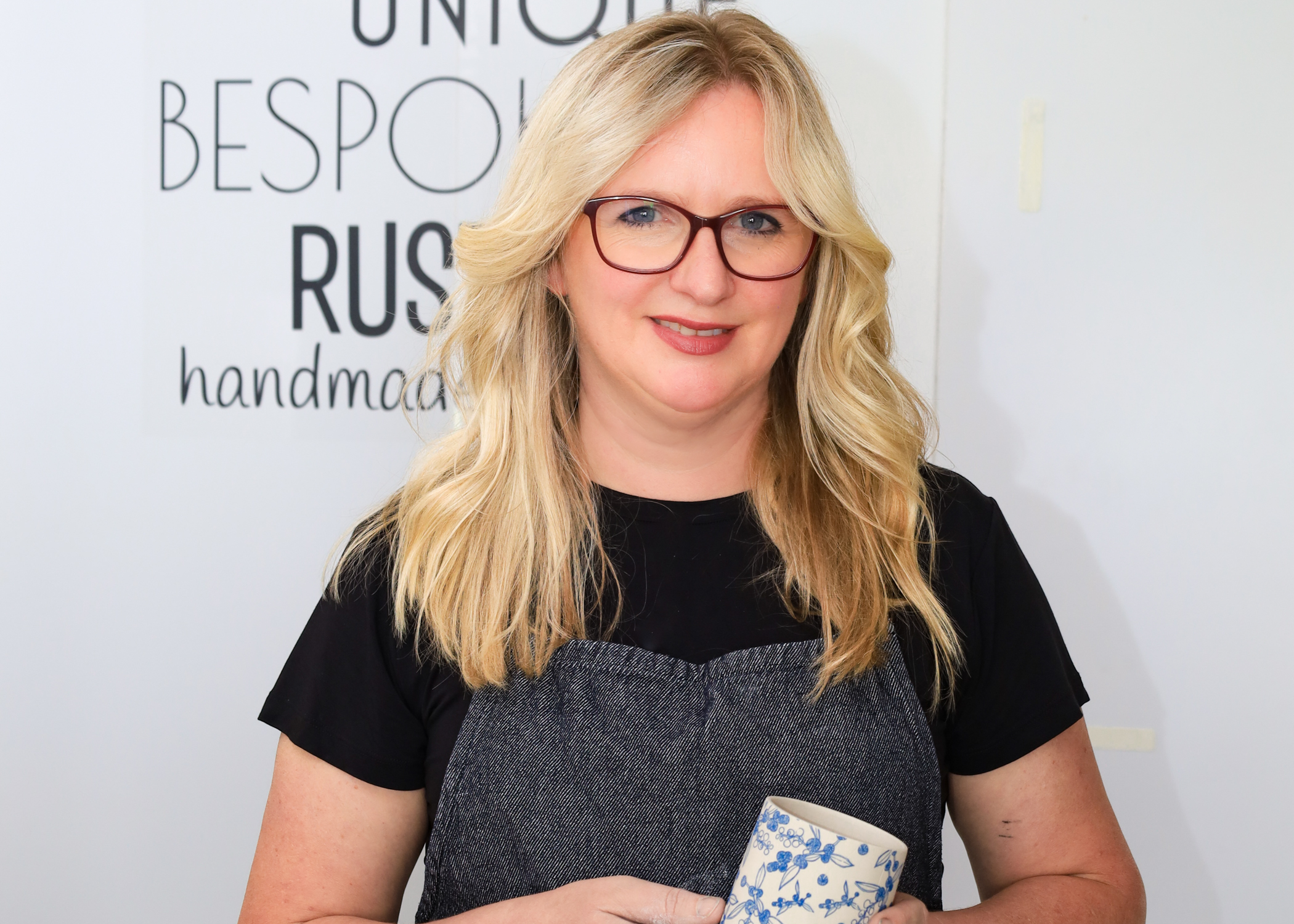 Picture of a woman holding a ceramic cup smiling to camera