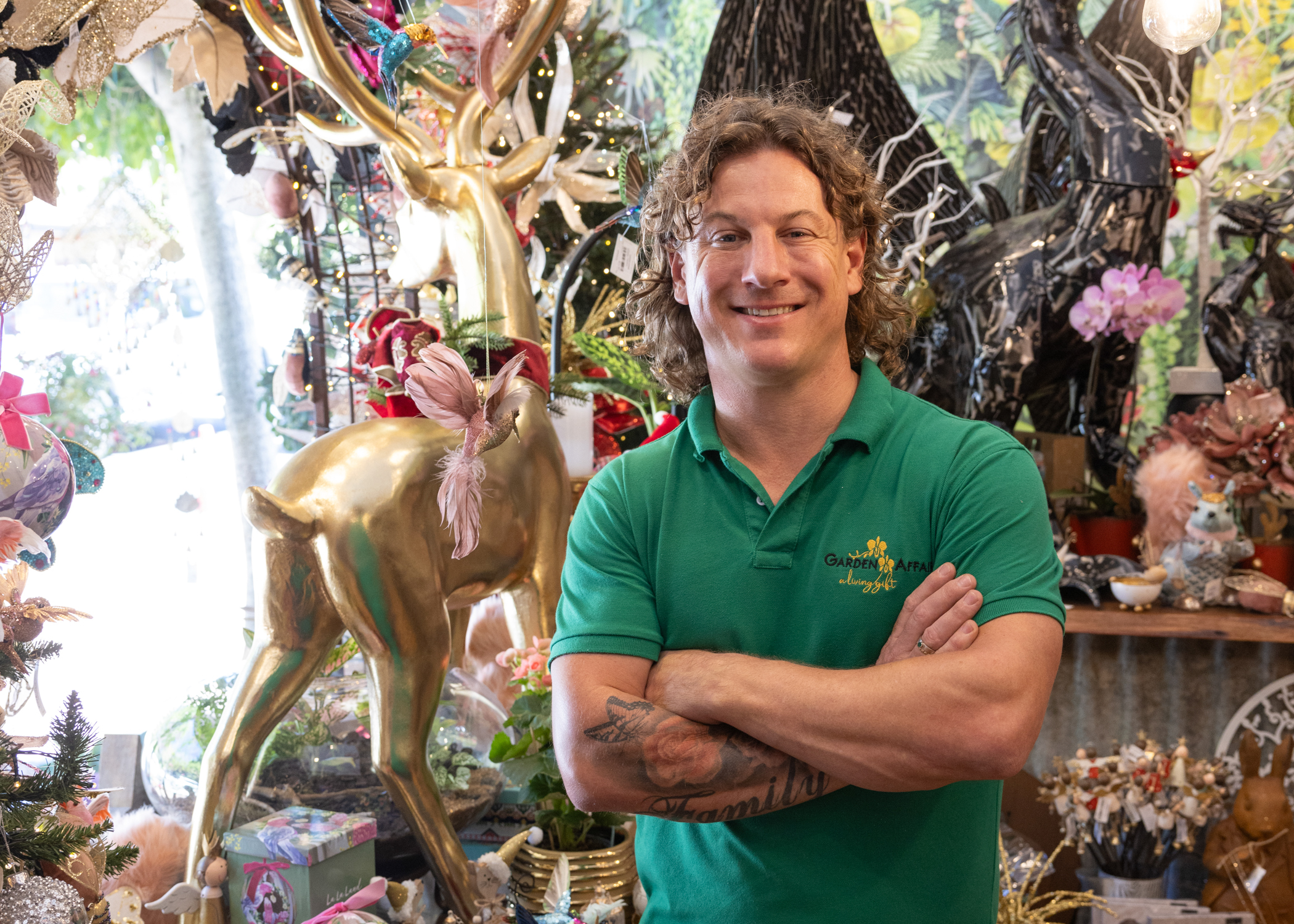 Man stands in gift shop with arms folded smiling at camera