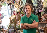 Man stands in gift shop with arms folded smiling at camera