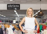 Person stands in front of a sign saying "obriens clothing co" in a clothing store