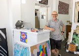 Manstandsinframingshopatreceptiondesksurroundedbyartworks