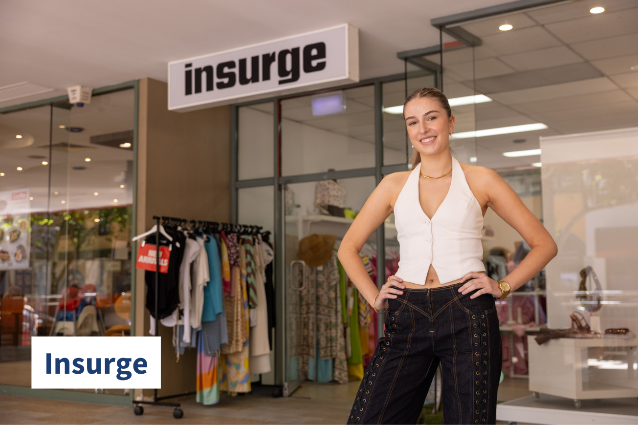 Woman stands outside fashion retail store with hands on hips