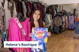 Woman stands in clothing store holding Shop Local sign