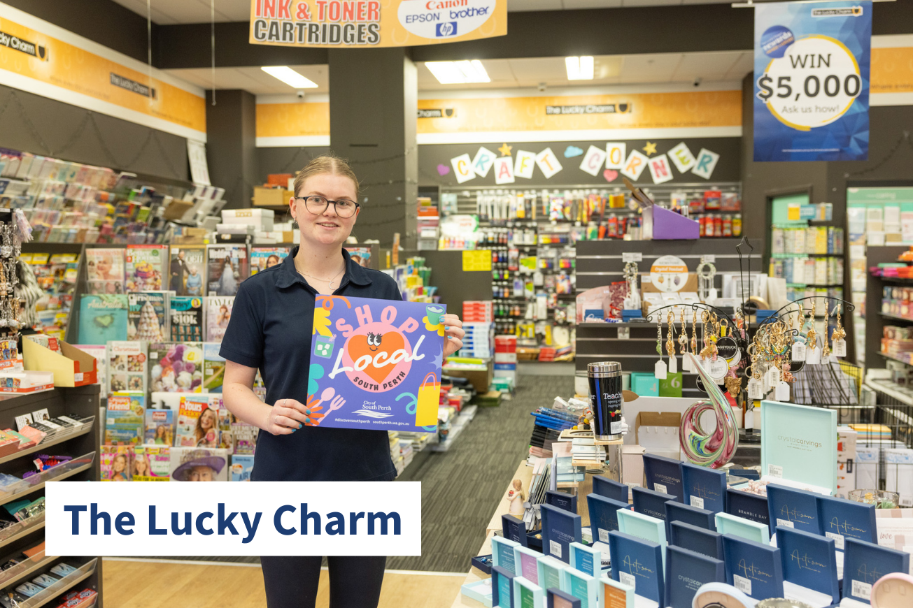 Person stands inside newsagency holding Shop Local sign