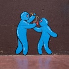 A wall mural with two blue characters sharing noodles from a single bowl.