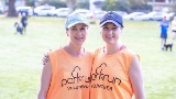 twowomensmilingatthecamerawearingparkrunvolunteershirtsatapark