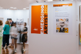 blurredpictureofemergingartistexhibitionopeningnightwithlargeposterartonwallsandpeoplemillingaboutthespace