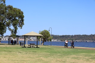 Peopleridingbicyclesandatpicnictableatriverforeshore