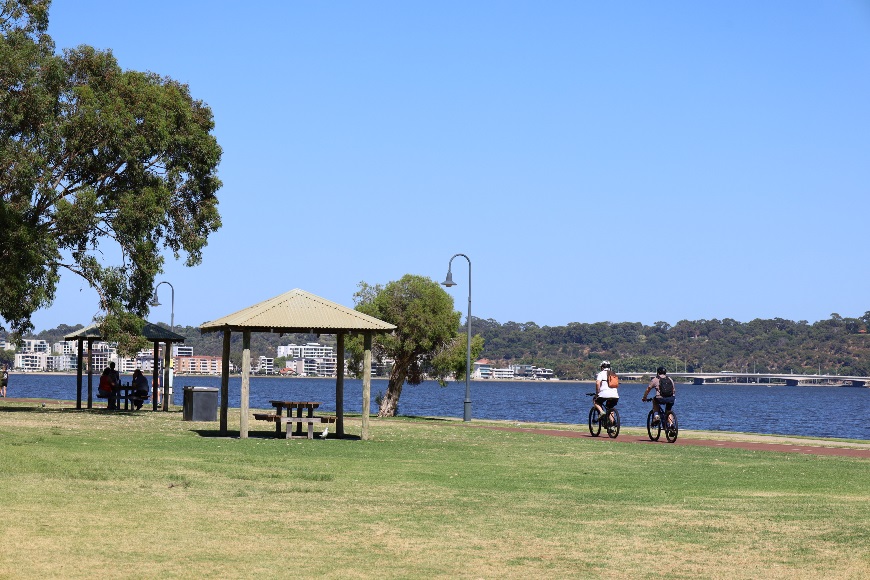 Peopleridingbicyclesandatpicnictableatriverforeshore