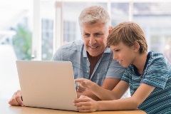 Youngboyhelpingseniormaleonthecomputer