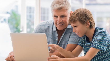 Youngboyhelpingseniormaleonthecomputer