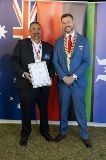 Two men smiling and holding a framed certificate.