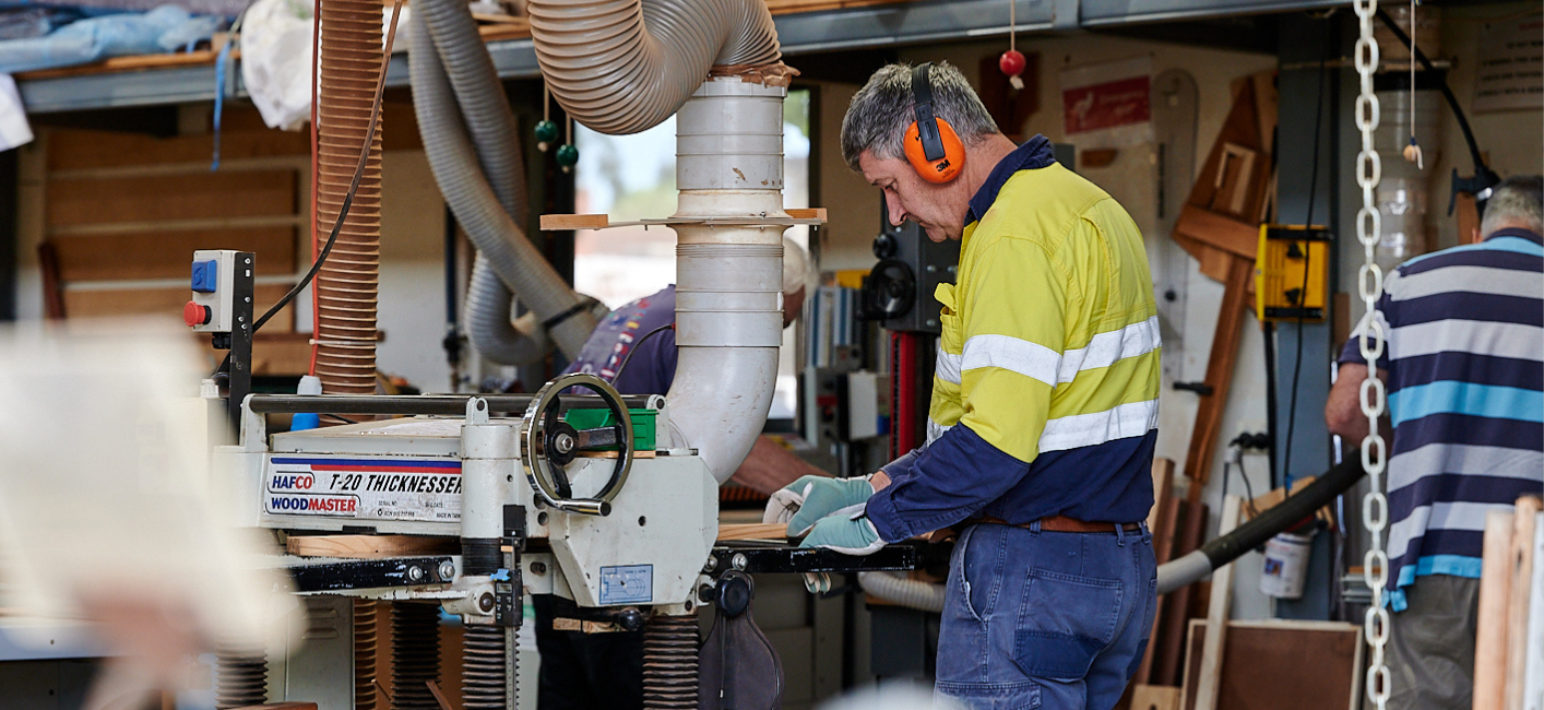 man wearing ear muffs working in shed