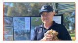 Smilingparkrangerholdingafluffydogwithaleashontheforeshore