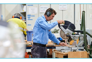 Personoperatingatablesawinaworkshopwearingearmuffs