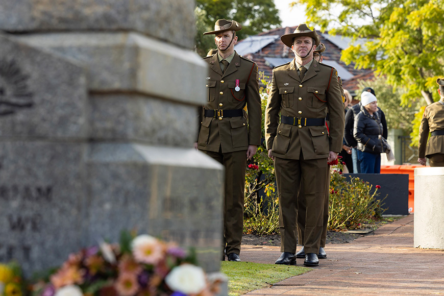 Two men in uniform standing in front of a stone memorial.