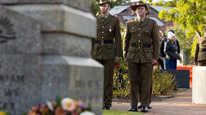 Twomeninuniformstandinginfrontofastonememorial