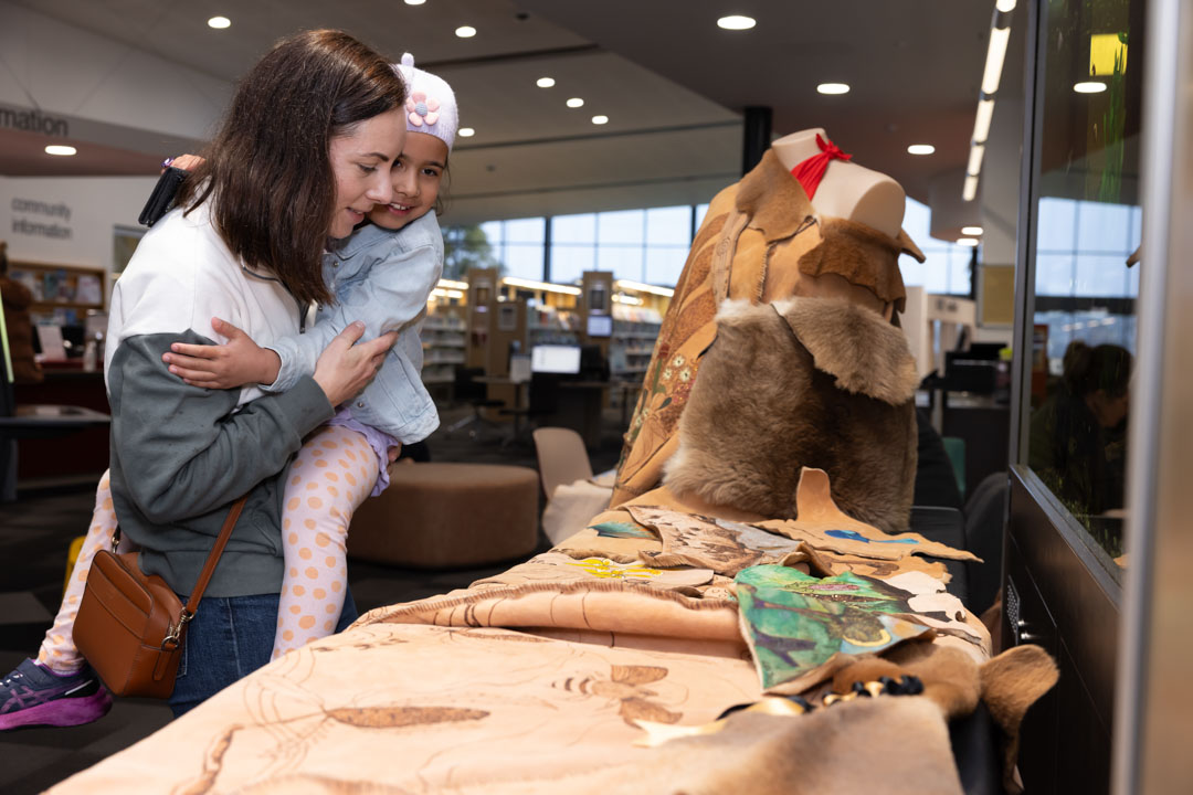 Woman and child looking at a kangaroo skin cloak artpiece.