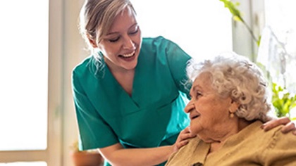 Ayoungerpersonsmilingandtoughingtheshouldersofanolderperson