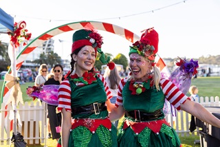 Twowomeninfestiveelfcostumessmilingatthecamera