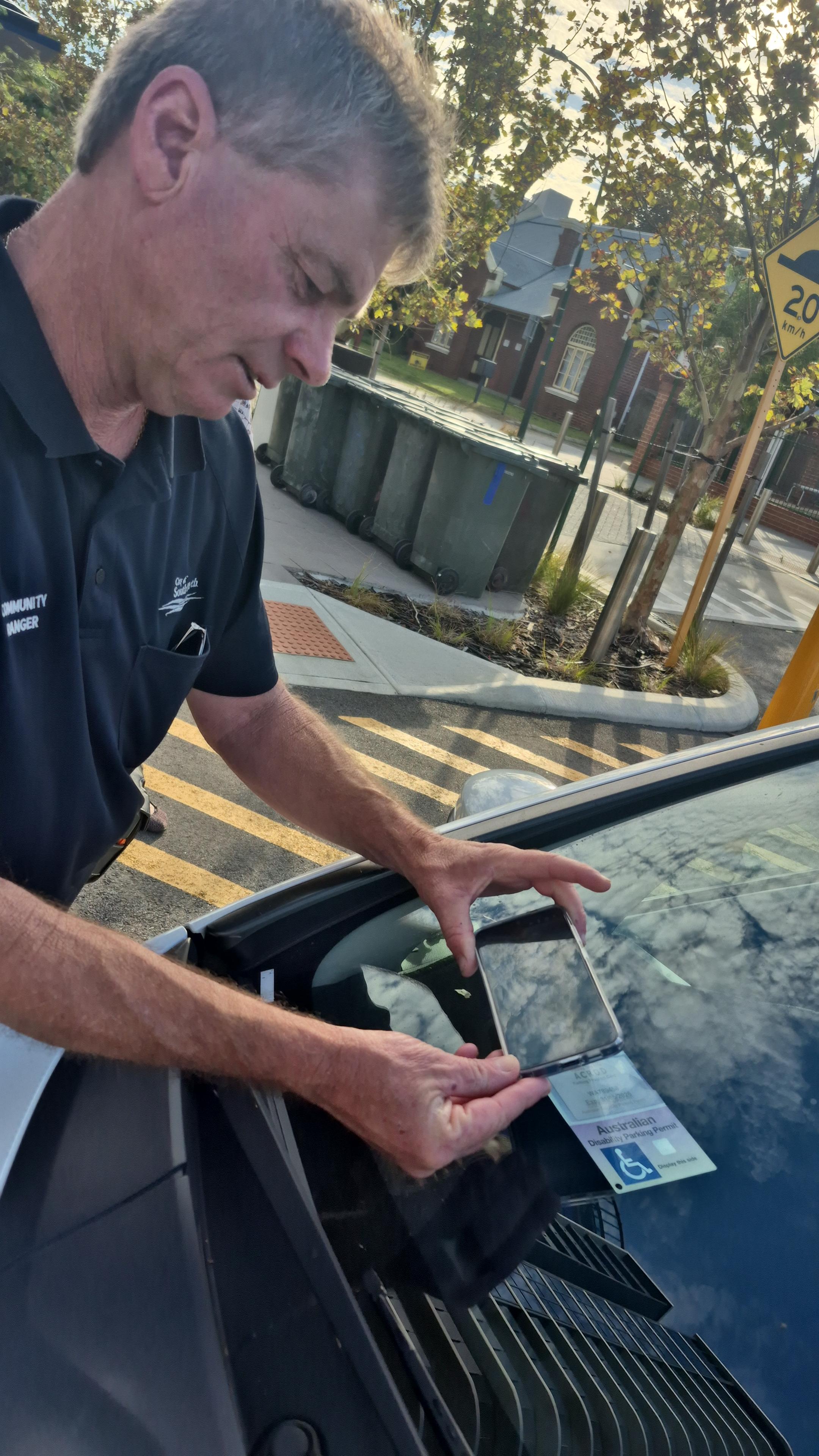 Man scanning ACROD sticker on car.