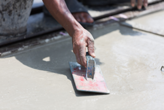 Acloseupofaworkersmoothingwetconcreteonafootpath