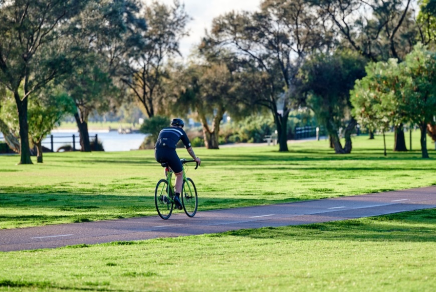 Manridinghisbikethroughaparkwithtreesandariveronacyclepath