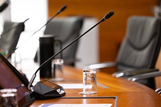 Microphonesattachedtoaglossywoodtablewithemptychairsaround