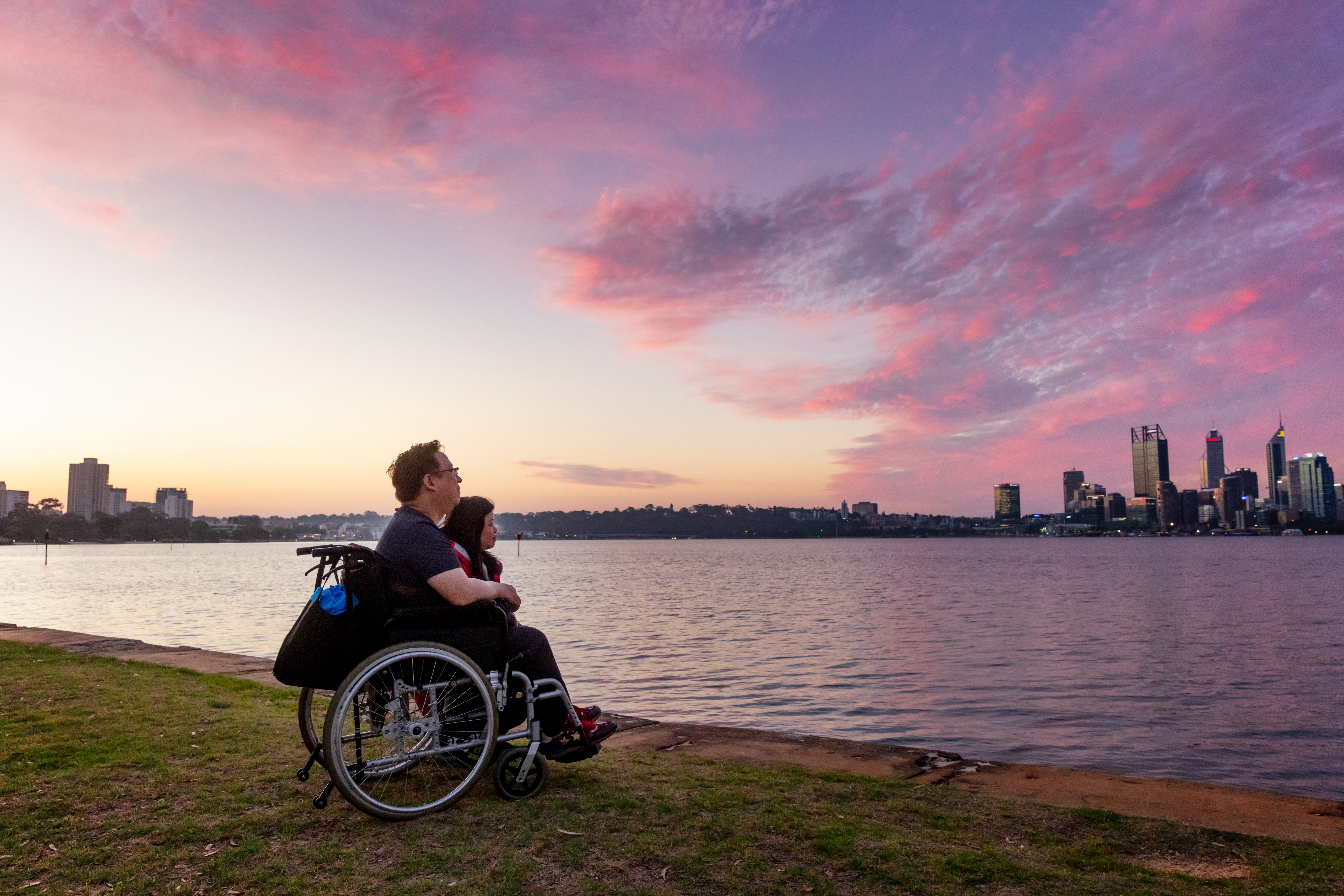 Person in wheelchair looking across river towards City buildings