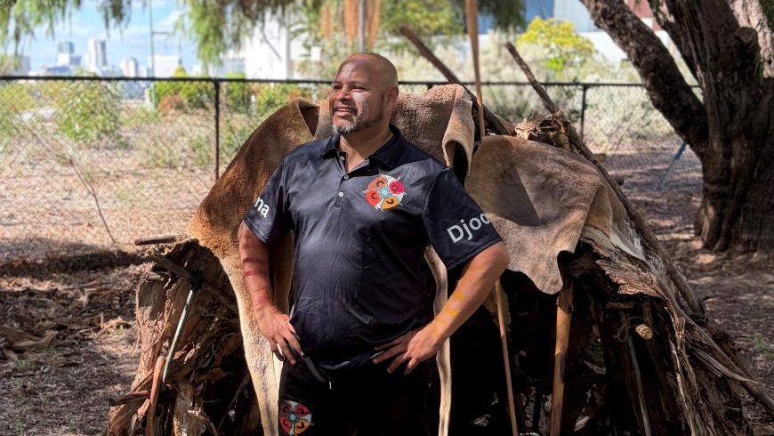 ManinfrontoftraditionalAboriginalhutwithkangarooskins