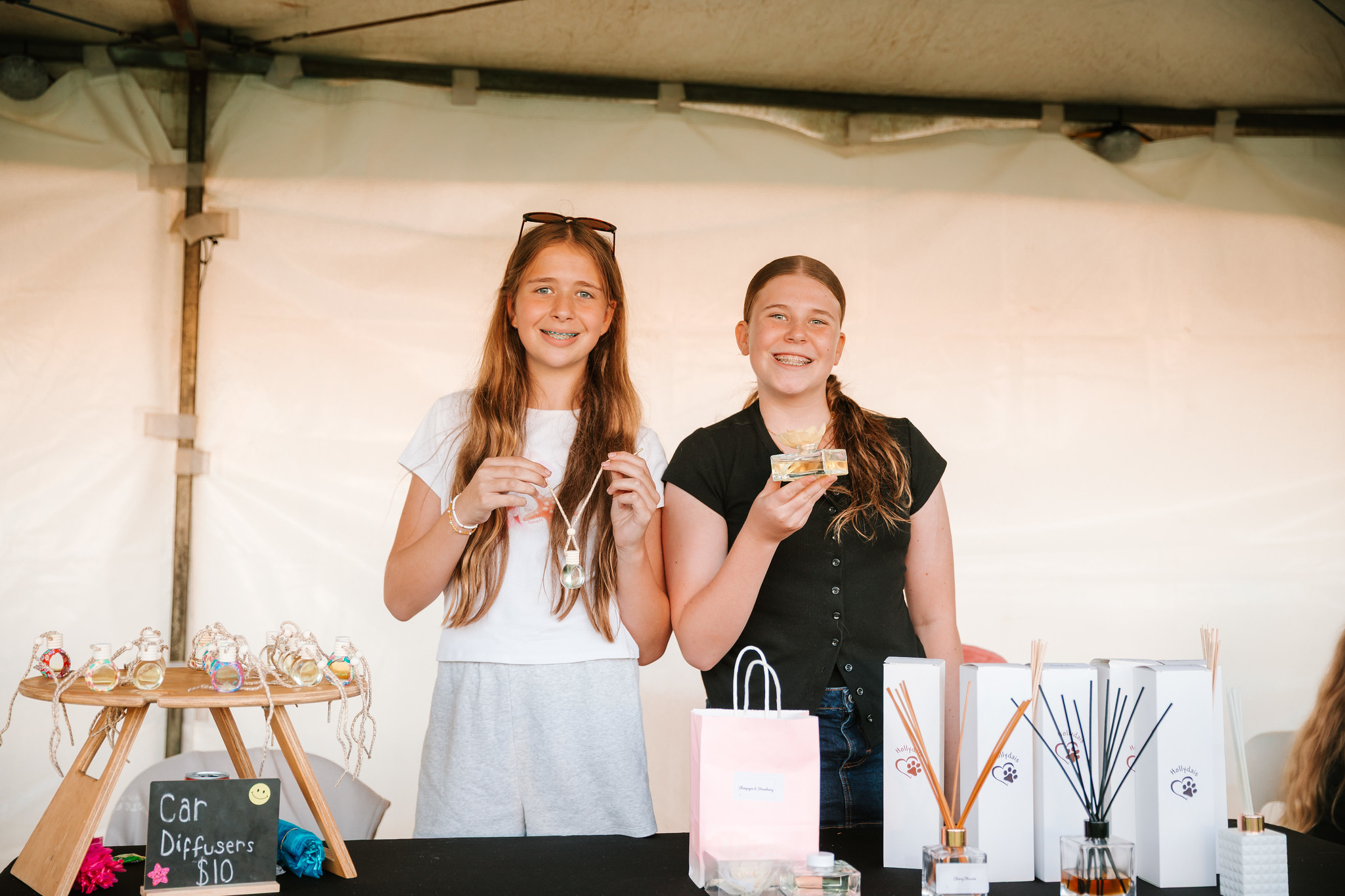 two young girls with the car diffusers they are selling at their stall.