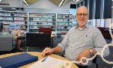 CareeradvisorBrettMouldensitsatadeskatManningLibrarysmilingwithnotesinfrontofhim