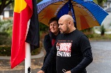 Manraisingaflagwithawomanstandingbehindholdinganumbrella