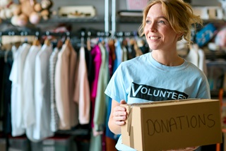 Awomanatanopshopholdingaboxofdonations
