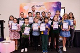 A group of children and a man standing in a group holding their awards