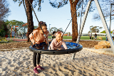 Motherpushingherbabydaughteronaroundswinginaparkplayground