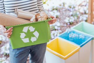 Someoneholdingagreenrecyclingtubwithpaperandcardboardinit