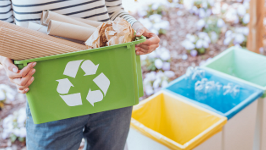 Someoneholdingagreenrecyclingtubwithpaperandcardboardinit